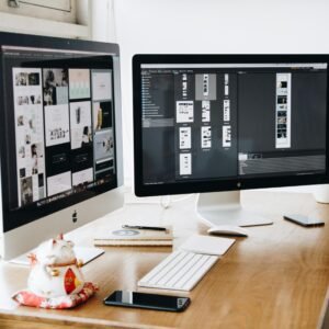 Two Imac's With Keyboard and Phones on Desk